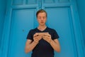 Young handsome man using mobile phone in front of blue door Royalty Free Stock Photo