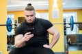 Young handsome man using phone while having exercise break in gym. Royalty Free Stock Photo