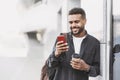 Young handsome man using smartphone in a city. Smiling student men texting on his mobile phone outdoors. Royalty Free Stock Photo