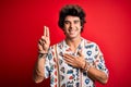 Young handsome man on vacation wearing summer shirt over isolated red background smiling swearing with hand on chest and fingers Royalty Free Stock Photo