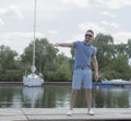 Young handsome man in walking at river pier. Handsome businessman invites to his boat. Summer time journey of successful