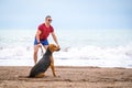 Young handsome man walks with big expressive dog though seashore. Deserted beach, happy pair, positive emotions Royalty Free Stock Photo