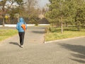 Young handsome man wearing a blue jacket with a sports bag, walking in Park, rear view