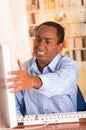 Young handsome man wearing blue office shirt sitting by computer making upset hand gestures and looking angry at screen Royalty Free Stock Photo