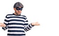 Young handsome man wearing burglar mask clueless and confused with open arms, no idea concept Royalty Free Stock Photo