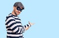 Young handsome man wearing burglar mask inviting to enter smiling natural with open hand Royalty Free Stock Photo