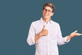 Young handsome man wearing business clothes and glasses showing palm hand and doing ok gesture with thumbs up, smiling happy and Royalty Free Stock Photo