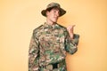 Young handsome man wearing camouflage army uniform smiling with happy face looking and pointing to the side with thumb up Royalty Free Stock Photo