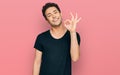 Young handsome man wearing casual black t shirt smiling positive doing ok sign with hand and fingers Royalty Free Stock Photo