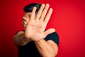 Young handsome man wearing casual black t-shirt standing over isolated red background covering eyes with hands and doing stop Royalty Free Stock Photo