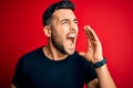 Young handsome man wearing casual black t-shirt standing over isolated red background shouting and screaming loud to side with Royalty Free Stock Photo