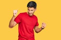 Young handsome man wearing casual red tshirt dancing happy and cheerful, smiling moving casual and confident listening to music Royalty Free Stock Photo