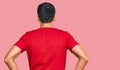 Young handsome man wearing casual red tshirt standing backwards looking away with arms on body Royalty Free Stock Photo