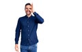 Young handsome man wearing casual shirt doing ok gesture with hand smiling, eye looking through fingers with happy face Royalty Free Stock Photo