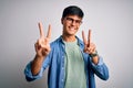Young handsome man wearing casual shirt and glasses over isolated white background smiling looking to the camera showing fingers Royalty Free Stock Photo