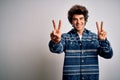 Young handsome man wearing casual shirt standing over isolated white background smiling looking to the camera showing fingers Royalty Free Stock Photo