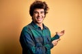 Young handsome man wearing casual shirt standing over isolated yellow background Inviting to enter smiling natural with open hand Royalty Free Stock Photo