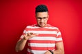 Young handsome man wearing casual striped t-shirt and glasses over isolated red background Moving away hands palms showing refusal Royalty Free Stock Photo