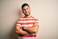 Young handsome man wearing casual striped t-shirt standing over isolated white background happy face smiling with crossed arms Royalty Free Stock Photo