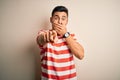 Young handsome man wearing casual striped t-shirt standing over isolated white background laughing at you, pointing finger to the Royalty Free Stock Photo
