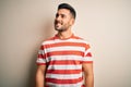 Young handsome man wearing casual striped t-shirt standing over isolated white background looking away to side with smile on face, Royalty Free Stock Photo