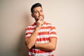 Young handsome man wearing casual striped t-shirt standing over isolated white background looking confident at the camera smiling Royalty Free Stock Photo