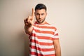 Young handsome man wearing casual striped t-shirt standing over isolated white background Pointing with finger up and angry Royalty Free Stock Photo