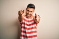 Young handsome man wearing casual striped t-shirt standing over isolated white background pointing to you and the camera with Royalty Free Stock Photo