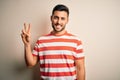 Young handsome man wearing casual striped t-shirt standing over isolated white background smiling looking to the camera showing Royalty Free Stock Photo