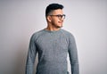 Young handsome man wearing casual sweater and glasses over isolated white background looking away to side with smile on face, Royalty Free Stock Photo