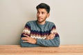 Young handsome man wearing casual sweater sitting on the table smiling looking to the side and staring away thinking Royalty Free Stock Photo