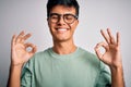 Young handsome man wearing casual t-shirt and glasses over isolated white background relax and smiling with eyes closed doing Royalty Free Stock Photo