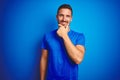 Young handsome man wearing casual t-shirt over blue isolated background looking confident at the camera smiling with crossed arms Royalty Free Stock Photo