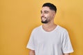 Young handsome man wearing casual t shirt over yellow background looking away to side with smile on face, natural expression Royalty Free Stock Photo