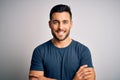 Young handsome man wearing casual t-shirt standing over isolated white background happy face smiling with crossed arms looking at Royalty Free Stock Photo