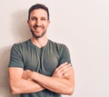 Young handsome man wearing casual t-shirt standing over isolated white background happy face smiling with crossed arms looking at Royalty Free Stock Photo