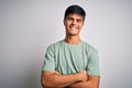 Young handsome man wearing casual t-shirt standing over isolated white background happy face smiling with crossed arms looking at Royalty Free Stock Photo