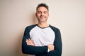 Young handsome man wearing casual t-shirt standing over isolated white background happy face smiling with crossed arms looking at Royalty Free Stock Photo