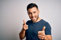 Young handsome man wearing casual t-shirt standing over isolated white background pointing fingers to camera with happy and funny Royalty Free Stock Photo