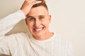 Young handsome man wearing casual t-shirt standing over isolated white background stressed with hand on head, shocked with shame Royalty Free Stock Photo