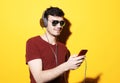 Young handsome man wearing casual t-shirt and sunglasses listening to music in headphones Royalty Free Stock Photo