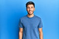 Young handsome man wearing casual tshirt over blue background with a happy and cool smile on face