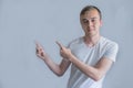 Young handsome man wearing casual white shirt pointing something on his side with his hand over gray background Royalty Free Stock Photo