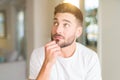 Young handsome man wearing casual white t-shirt at home with hand on chin thinking about question, pensive expression Royalty Free Stock Photo