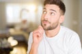 Young handsome man wearing casual white t-shirt at home with hand on chin thinking about question, pensive expression Royalty Free Stock Photo