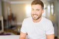 Young handsome man wearing casual white t-shirt at home looking away to side with smile on face, natural expression Royalty Free Stock Photo