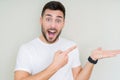 Young handsome man wearing casual white t-shirt over isolated background amazed and smiling to the camera while presenting with Royalty Free Stock Photo