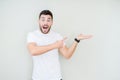 Young handsome man wearing casual white t-shirt over isolated background amazed and smiling to the camera while presenting with Royalty Free Stock Photo