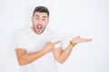 Young handsome man wearing casual white t-shirt over white isolated background amazed and smiling to the camera while presenting Royalty Free Stock Photo