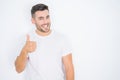 Young handsome man wearing casual white t-shirt over white isolated background doing happy thumbs up gesture with hand Royalty Free Stock Photo